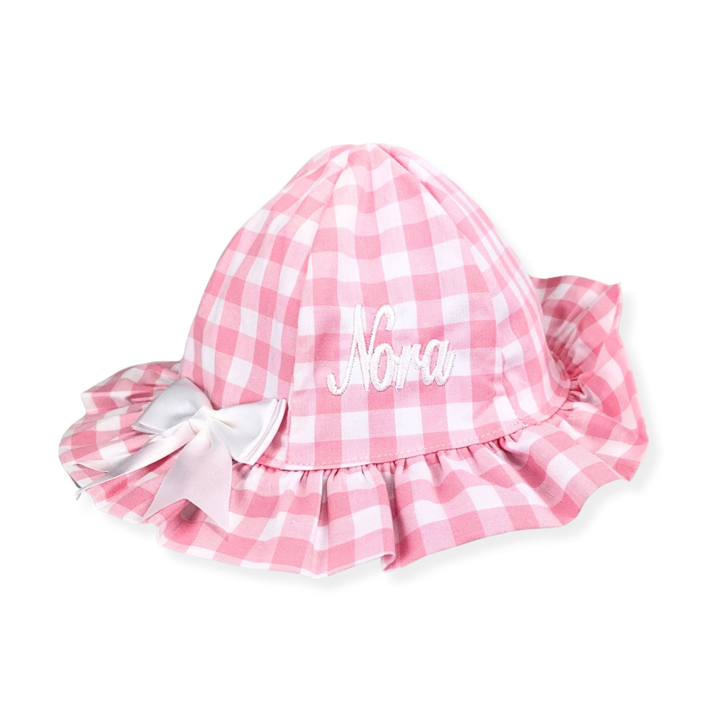 Pink gingham baby hat with ruffles and a bow on a white background