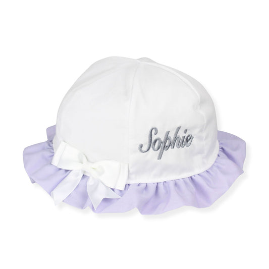 White baby hat with lavender ruffle and embroidered name on a white background