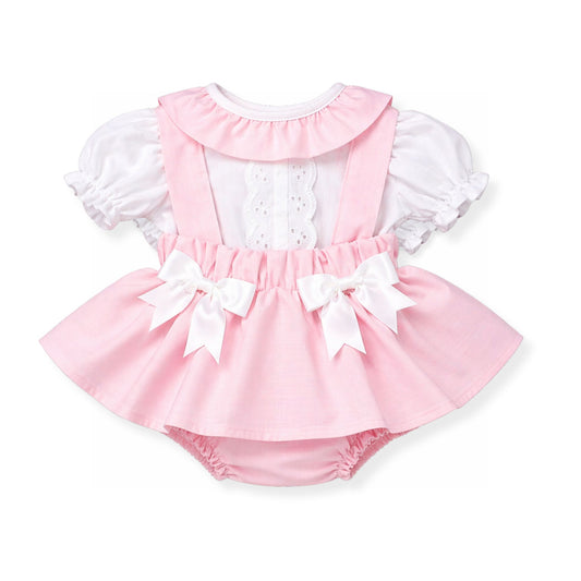 Pink baby dress with white ruffles and bows on a white background