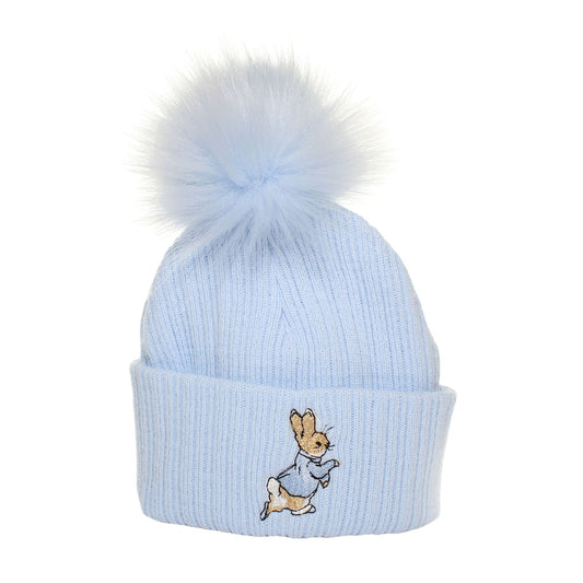 Light blue knit beanie with a fluffy pom-pom and embroidered character on a white background