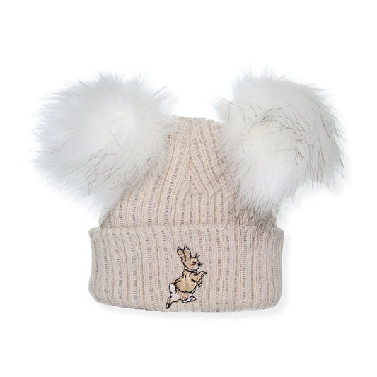 Beige knit beanie with white fur pom-poms and a embroidered design on a white background
