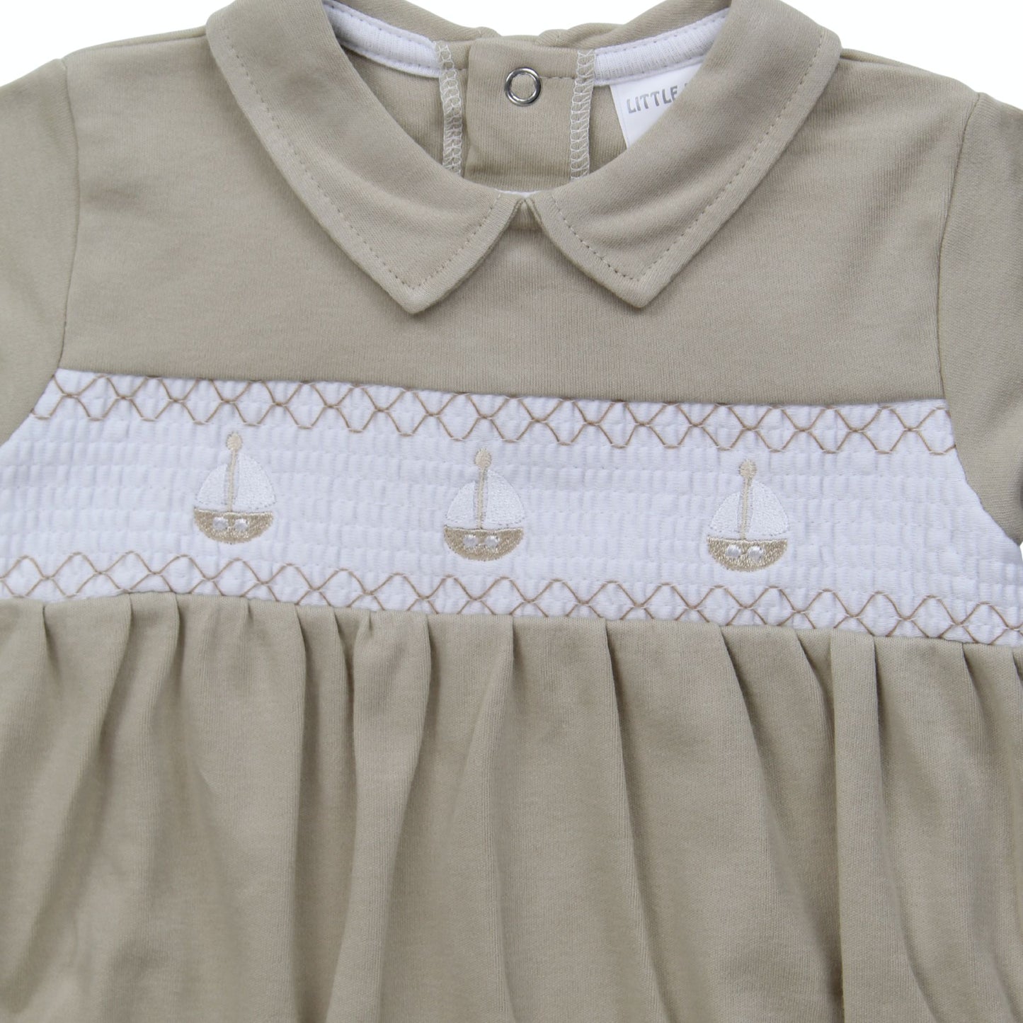 Beige baby dress with white smocked bodice and collar, featuring sailboat design.