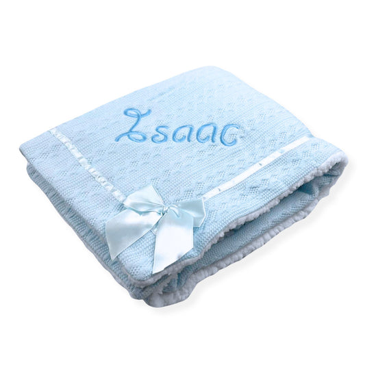 Blue baby blanket with embroidered name and bow on a white background