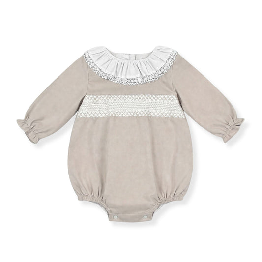 Beige baby romper with white lace details on a white background