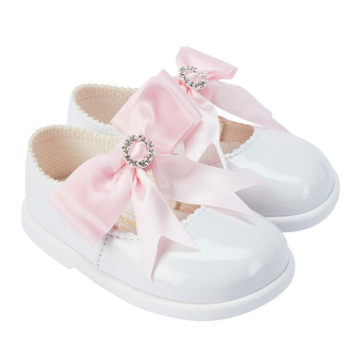 White shoes with pink ribbons and decorative bows on a white background