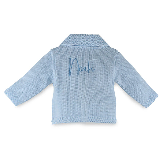 Personalised blue knitted baby cardigan by Dandelion with embroidered name on the back, traditional collar detail and button fastening. Made in Portugal. Available from newborn to 6-12 months.