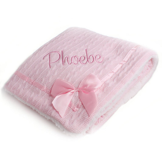 Pink baby blanket with a bow and embroidered name on a white background