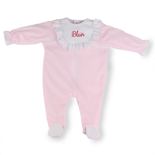 Pink baby onesie with white ruffled collar and embroidered name on a white background