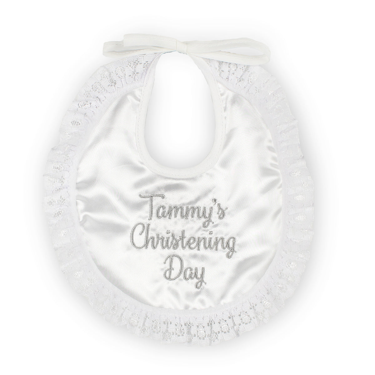 A white satin baby bib with a ruffled lace border and a small bow at the neck, featuring the text 'Tammy's Christening Day' in silver cursive embroidery.