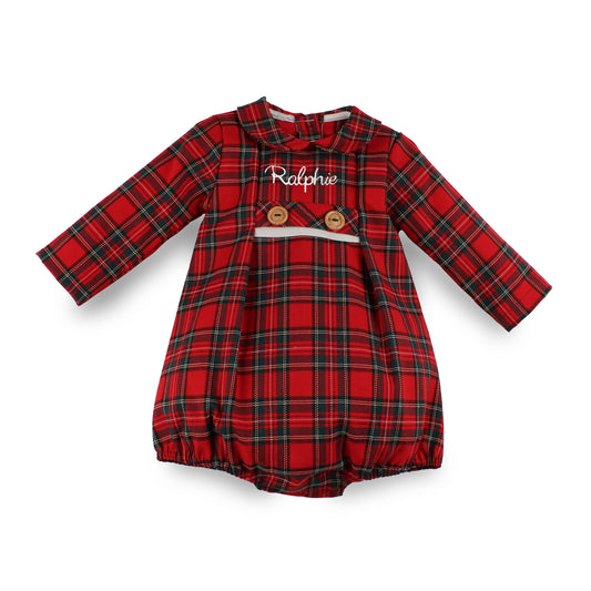A baby long-sleeve romper in a red and black tartan plaid pattern, featuring a Peter Pan collar, two wooden buttons, and a decorative white ribbon across the chest.