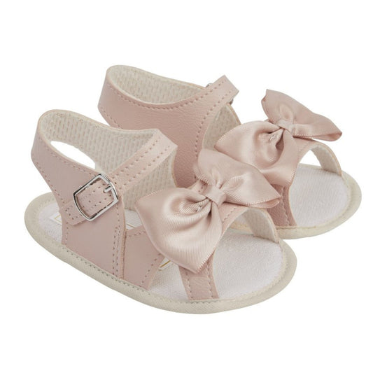 Pink baby sandals with bow details on a white background
