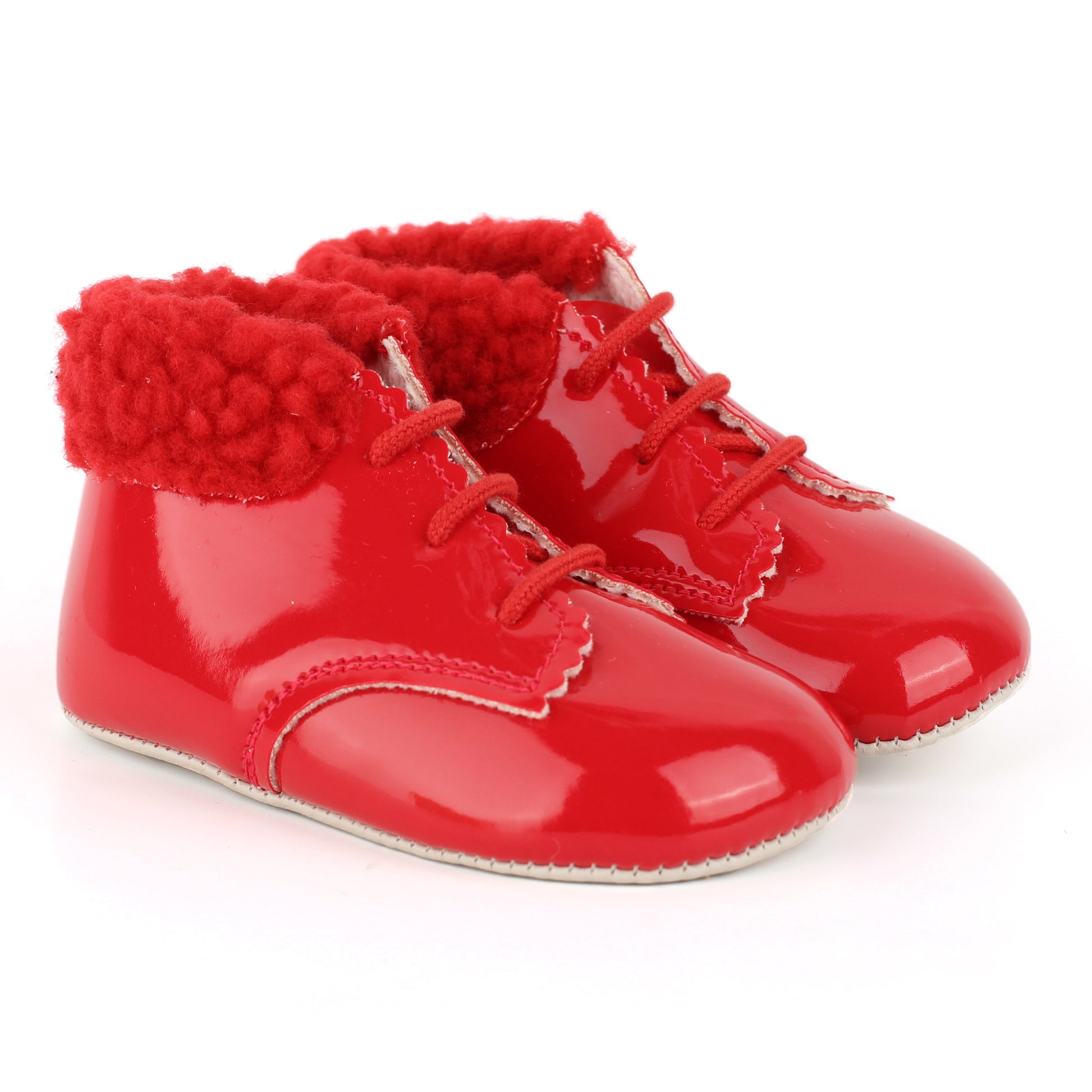 A pair of red patent leather baby boots with red faux-fur trim and red laces, shown on a white background.