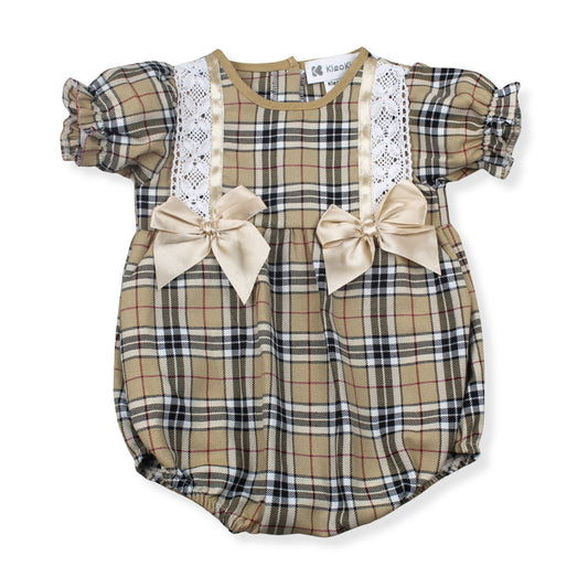 Tartan baby romper with lace details and bows on a white background