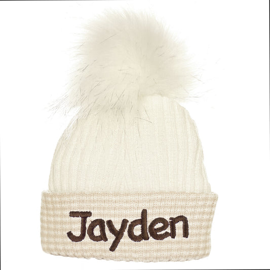 Beige beanie with white fur pom-pom and 'Jayden' embroidered on a white background
