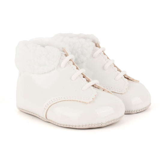 A pair of baby boots in glossy white faux leather with white faux fur trim and white laces, shown on a clean white background.